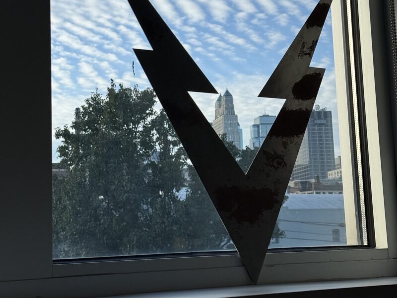 VOLTAGE V cutout in the office window framing the downtown Kansas City skyline